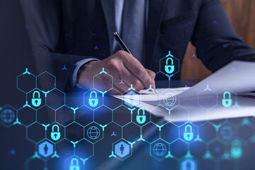 A businessman in formal wear signing the contract to prevent probability of risks in cyber security. Padlock Hologram icons over the working desk.