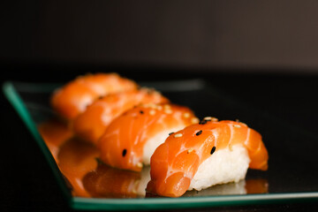 Close up of nigiri sushi set with chopsticks and soya on black background 