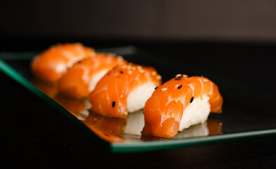 Close up of nigiri sushi set with chopsticks and soya on black background 