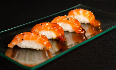 Close up of nigiri sushi set with chopsticks and soya on black background 