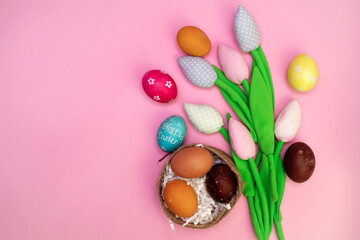 Easter background with painted eggs in nest and colorful tulips. Top view with copy space