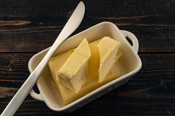 butter and knife in white dish on wooden table
