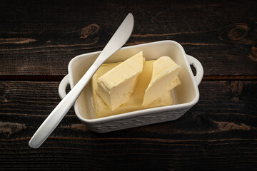 butter and knife in white dish on wooden table