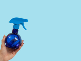 hand is holding a spray bottle on blue . space fot text