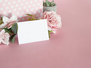 Pink flowers and blank white paper on pink background.	