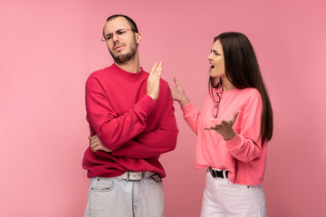Fototapeta premium Photo of couple argues and looks unhappy together, isolated over pink background