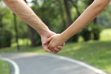 Rear view and close up young romantic couple wearing sportswear holding hands and walking together in the park in summer season (healthy or friendship valentine concept)