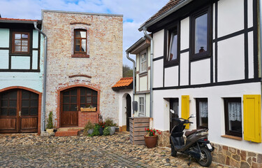 Motorbike near porch on cobblestone in the medieval yard in an old European town