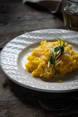 Rustic dinner with risotto all Milanese. Risotto with Saffron and parmesan on white plate on wooden table. 