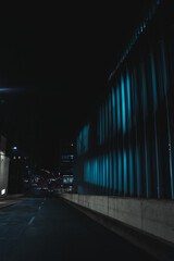 Street lights illuminating an outdoor concrete wall with vertical indentations