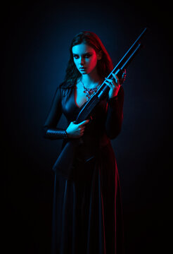 Vampire in black long corset dress in smoke holding a gun