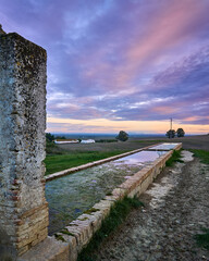 Atardecer sobre el pilar de agua de Carmona con un color azul y rosa sobre la vega o el sembrado verde