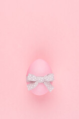Simplicity and purity easter background - egg with grey ribbon on pink pastel color, vertical.