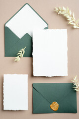 Vintage wedding stationery top view. Flat lay green envelopes with wax seal stamp, blank paper cards, dried flowers. Wedding invitation design.