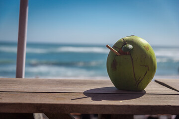 Coconut with a tube on the windowsill. Ocean view. Coconut water drink