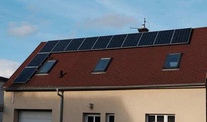Red tile roof of home with modern roof windows and solar panels. Eco-friendly alternative energy for house. Residential family house suburban. Home solar panel.