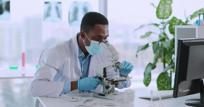 Afro-americcan young biologist doctor examining bacteria in medical office laboratory taking samples. Vaccination development.