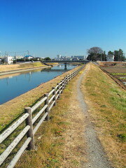 Fototapeta na wymiar 早春の放水路と小道のある土手風景