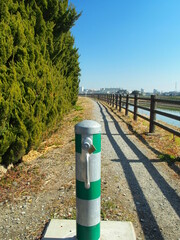 早春の車止めのある放水路土手の散策路風景