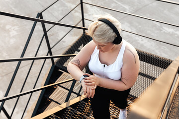 Hight angle view of a curvy woman stepping up on stairs checking pulse on a smartwatch