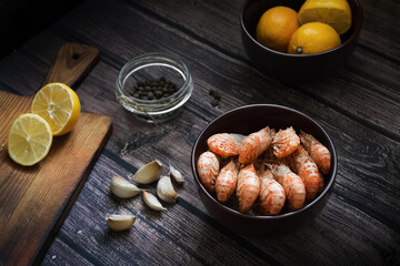 Boiled Greenlandic prawns with spices, garlic and lemon on a wooden background. Preparing a seafood dinner. A quick and healthy dinner.Rustic style
