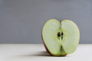 Half an apple close-up on a gray background. A source of vitamins and trace elements. Healthy eating.Healthy snack.Minimalist composition. The concept of minimalism in food photography.