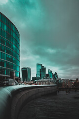 View of massive skyscrapers on the other side of the river thames, seen from the londons city hall area. Financial district glowing teal in the distance on a cold winter day