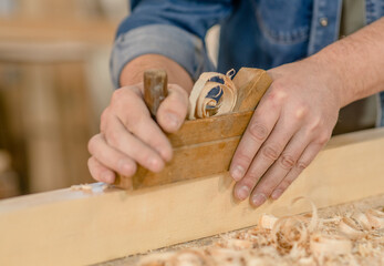Hands of a carpenter is planing a wood in a workshop - obrazy, fototapety, plakaty