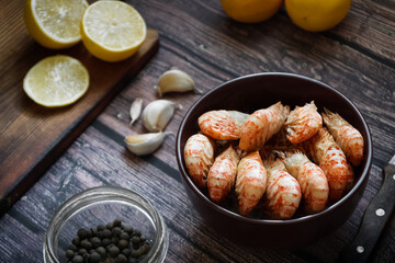Greenlandic shrimps. Boiled shrimp on a dark background with lemon and spices.Preparation of a dietary dish . Protein products. Source of omega 3 and omega 6 acids. Rustic style