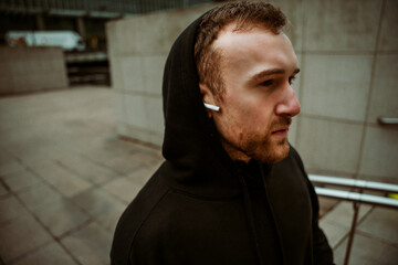 Fototapeta premium Portrait caucasian male athlete running in city listening to music with earphones