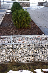 Obraz premium A fragment of space arrangement with the use of gabions. Separation of the street from the park area. Winter.