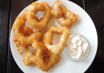 calamares a la romana, fried battered squid rings   with sauce on an old table