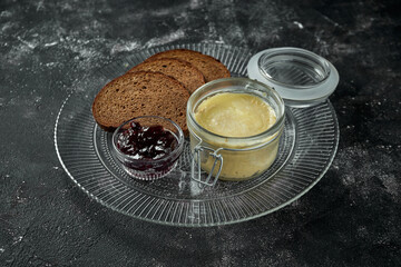Perfect appetizer - chicken liver pate in jar with jam and rye bread on black background. Close up,...