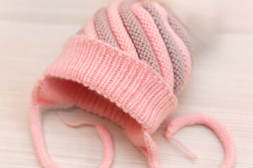 Pink children's knitted wool hat with a pompom, on a white background