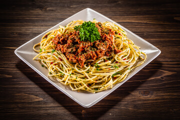 Spaghetti with marinara sauce, meat and parmesan on wooden table 