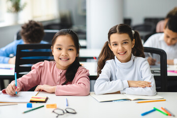 Portrait of small girls sitting at desk in classroom