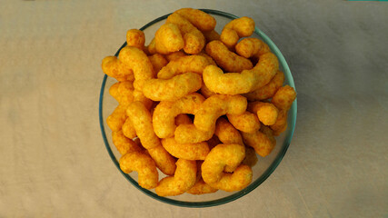 peanut flips . lots of corn sticks in peanut glaze in a glass round bowl in the middle on a gray light background top view