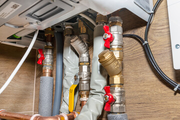 Natural gas valves and pipes in a modern home boiler room with ceramic tiles.