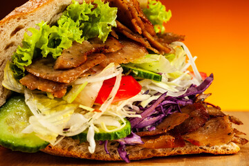 Kebab - grilled meat, bread and vegetables against orange gradient background