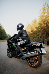 Motorcyclist in a helmet on a motorcycle on a country road. Guy driving a bike during a trip. Riding a modern sports motorcycle on the highway