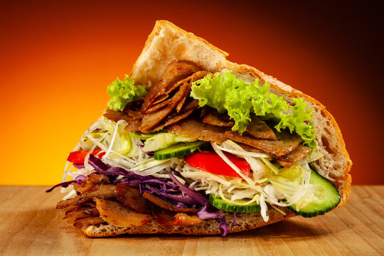 Kebab - grilled meat, bread and vegetables against orange gradient background