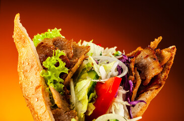 Kebab - grilled meat, bread and vegetables against orange gradient background