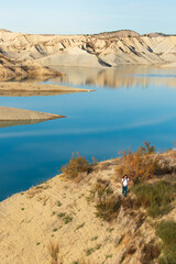 young mountaineer with a backpack hiking in an oasis-like scenario with a blue lake