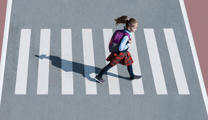 Schoolgirl crossing road on way to school. Zebra traffic walk way in the city. Concept pedestrians passing a crosswalk.  Stylish young teen girl walking with backpack. Active child. Top view
