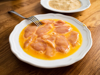Fresh raw chicken nuggets in raw scrambled eggs ready to be fried