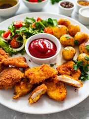 Fried breaded chicken nuggets with fried potatoes  and fresh vegetables
