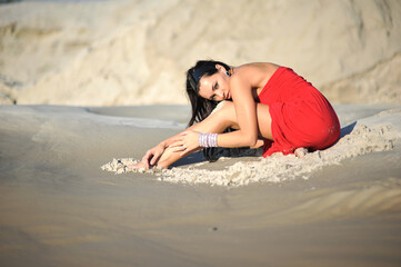 Fototapeta premium Beautiful woman in a red dress in the desert
