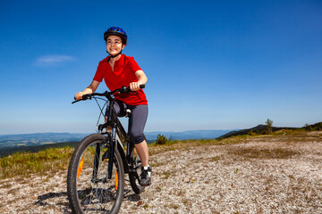 Young woman riding bicycle on country road
