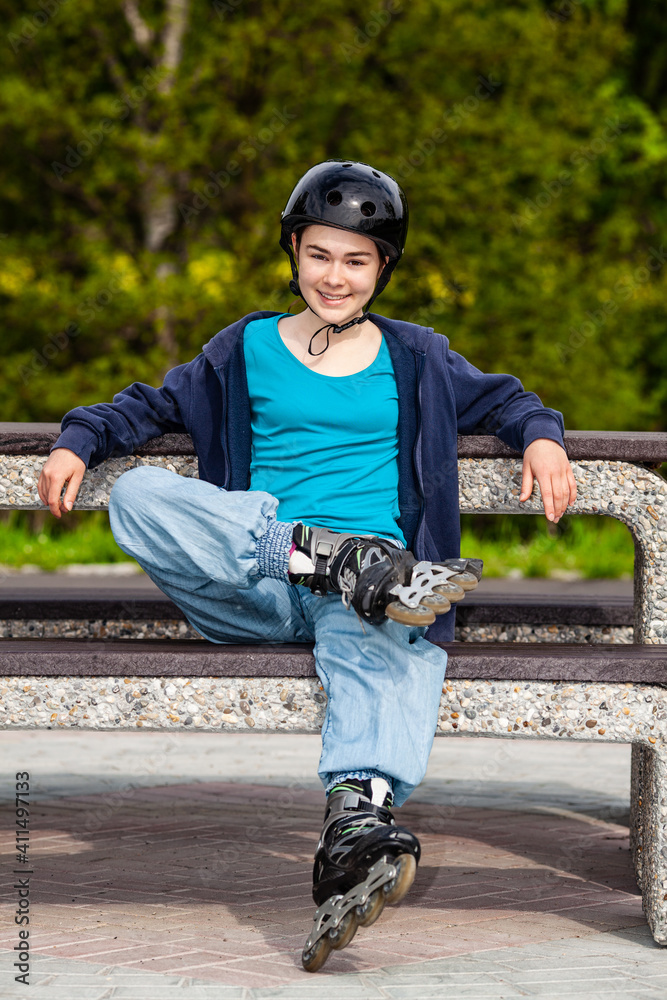 Wall mural Teenage girl sitting on bench after rollerblading 