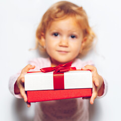 Close-up of gift box with red ribbon bow in children girl hands.